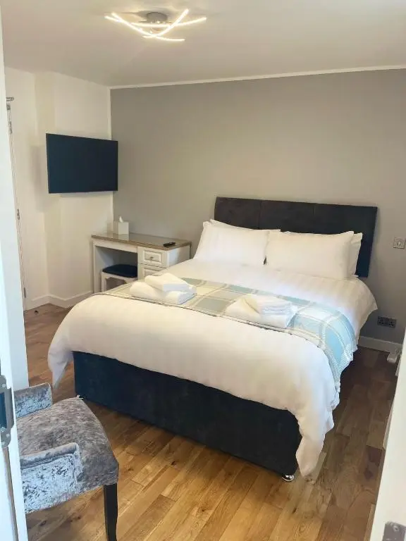a bedroom with a large bed and a chair at Inverness Highland Apartment in Inverness