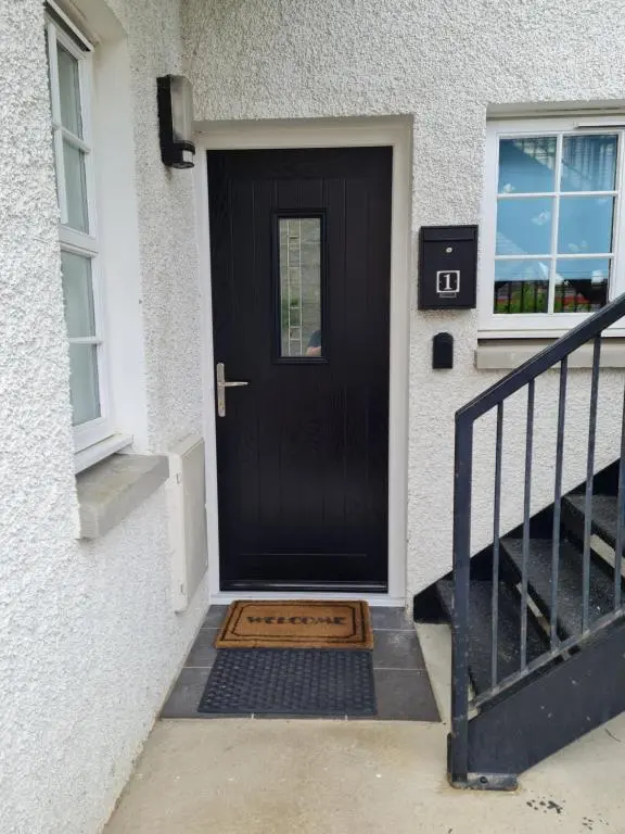 a black front door of a house with a stopper at 1 Golf Mews in Ballater