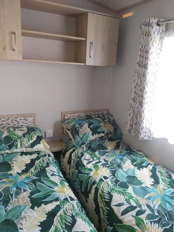 two beds in a small room with flowers at Caravan By The Sea in Elgin