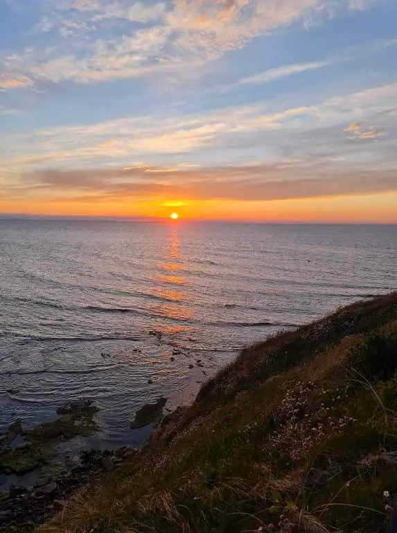 a sunset over the ocean with the sun setting at Caravan By The Sea in Elgin