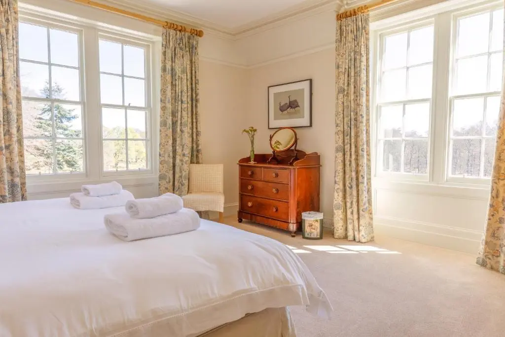 a bedroom with a bed and a dresser and windows at Dalgheal in Evanton