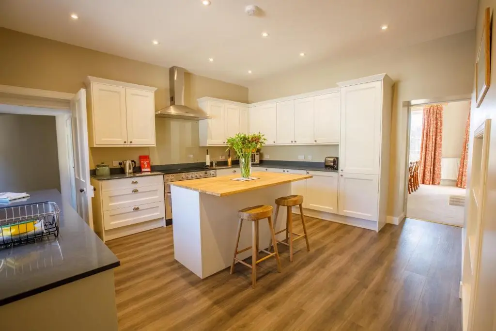 a kitchen with white cabinets and a kitchen island with stools at Dalgheal in Evanton