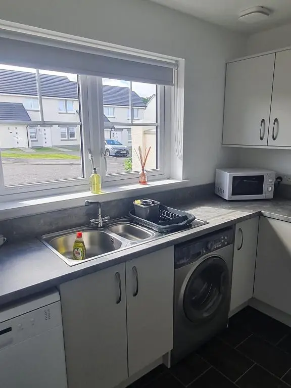 a kitchen with a sink and a washing machine at Faillie in Inverness